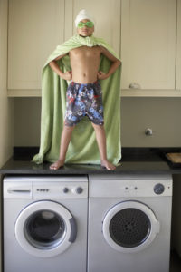 Young Super Hero Standing on Laundry Machines