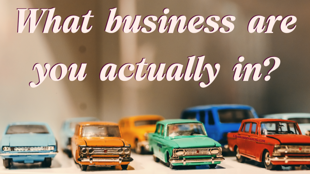 A banner image that reads "What business are you actually in? floating in the space above a row of die-cast toy cars in a rainbow of colors and styles.